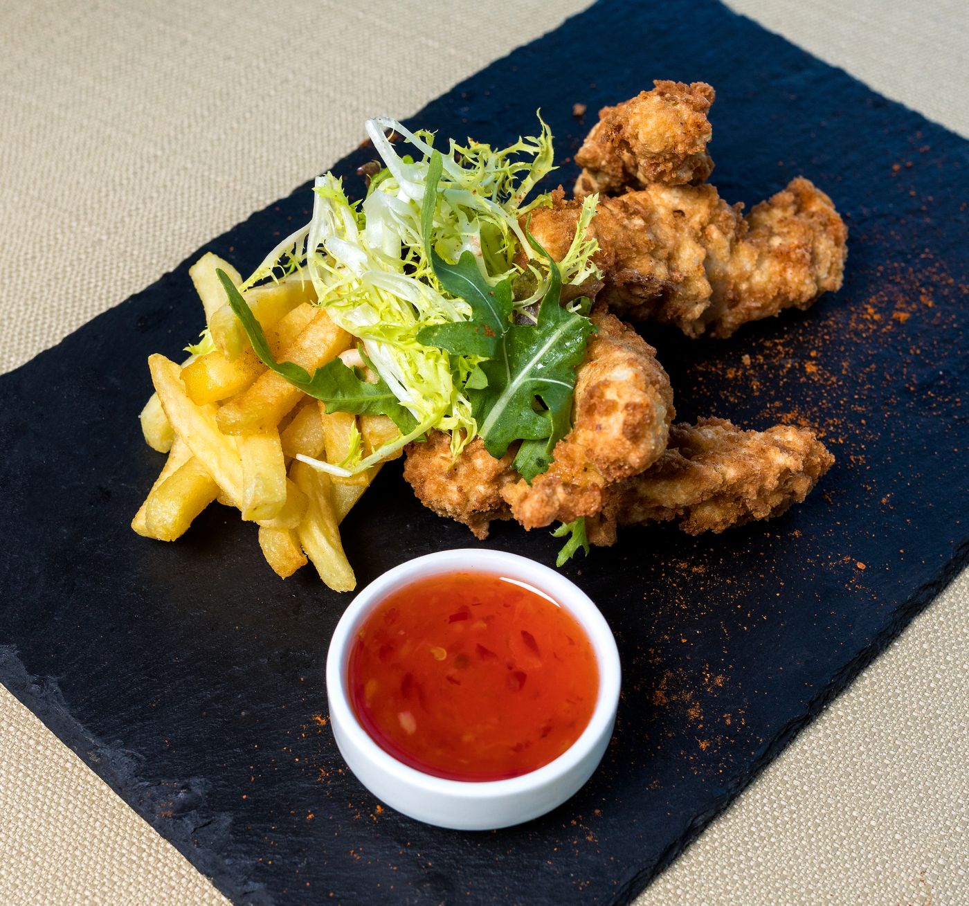 Assiette de tenders de poulet, frites et sauce sucrée piquante